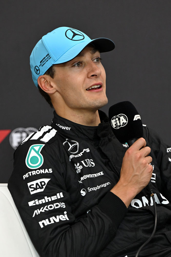 Formula 1 -kuljettaja George Russell mikrofoni oikeassa kädessään.