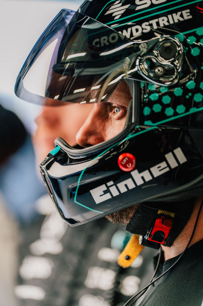 Formula 1 -miehistön jäsenellä on kypärä päässään ja hän katsoo sivulle keskittyneesti.